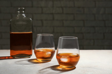 Glasses and bottle of whiskey on grey table