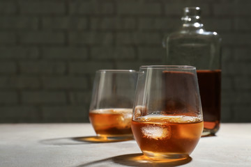 Glasses and bottle of whiskey on grey table