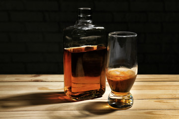 Glass and bottle of whiskey on wooden table