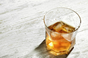 Glass of whiskey on light wooden table