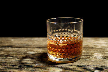 Glass of whiskey on wooden table