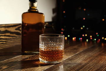 Glass and bottle of whiskey on wooden table