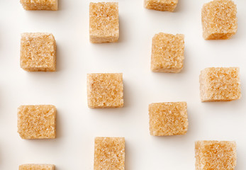 Brown cane sugar cubes on white background