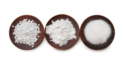 Plates with different kinds of sugar on white background