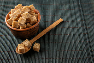 Bowl and spoon with brown cane sugar on dark table