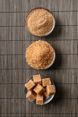 Bowls with different types of brown cane sugar on table