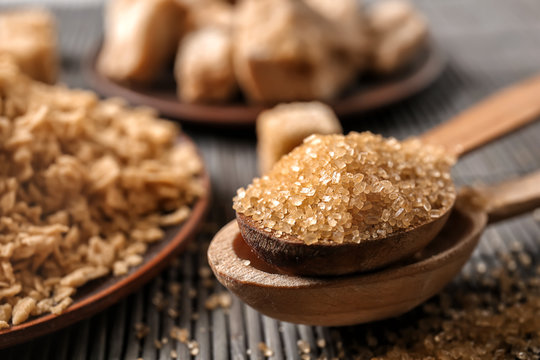Wooden spoons with brown sugar on table, closeup