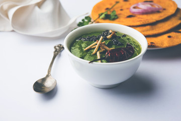 Makki di roti with sarson ka saag, popular punjabi main course recipe in winters made using corn breads mustard leaves curry. served over moody background. selective focus