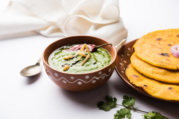 Makki di roti with sarson ka saag, popular punjabi main course recipe in winters made using corn breads mustard leaves curry. served over moody background. selective focus