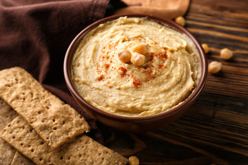 Bowl with tasty hummus on wooden table