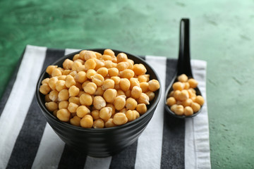 Bowl with chickpeas on color background