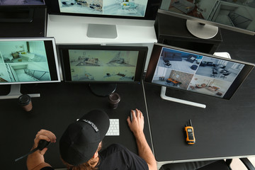 Security guard monitoring modern CCTV cameras in surveillance room