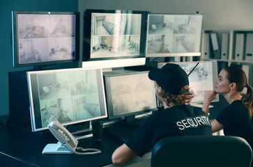 Security guards monitoring modern CCTV cameras in surveillance room