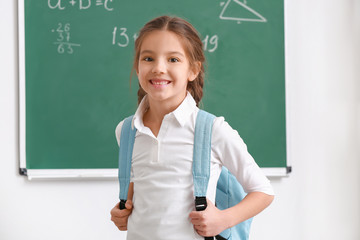 Cute girl with backpack in classroom