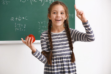 Cute girl with raised index finger in classroom