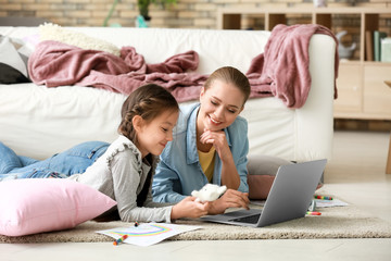 Cute girl with mother doing homework at home