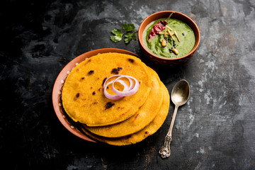Makki di roti with sarson ka saag, popular punjabi main course recipe in winters made using corn breads mustard leaves curry. served over moody background. selective focus