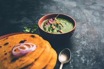Makki di roti with sarson ka saag, popular punjabi main course recipe in winters made using corn breads mustard leaves curry. served over moody background. selective focus