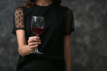 Beautiful young woman with glass of wine on dark background