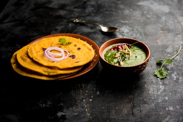 Makki di roti with sarson ka saag, popular punjabi main course recipe in winters made using corn breads mustard leaves curry. served over moody background. selective focus