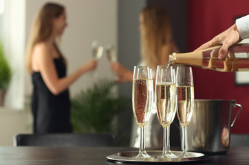 Waiter pouring champagne in glasses at party