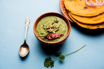 Makki di roti with sarson ka saag, popular punjabi main course recipe in winters made using corn breads mustard leaves curry. served over moody background. selective focus