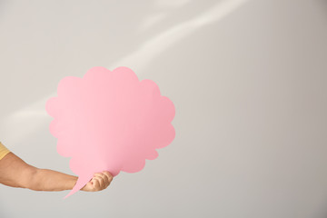 Hand of senior woman with blank speech bubble on light background