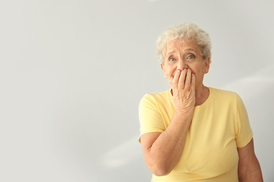 Portrait of elderly woman after making mistake on light background