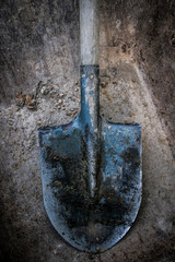Dirty shovel soiled in the soil and clay. Old work tool, deep hole. 