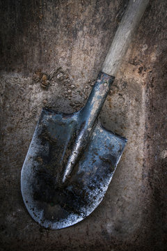 Dirty shovel soiled in the soil and clay. Old work tool, deep hole. 
