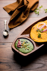 Makki di roti with sarson ka saag, popular punjabi main course recipe in winters made using corn breads mustard leaves curry. served over moody background. selective focus