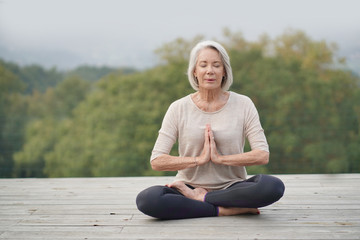   Serene senior woman meditating outdoors