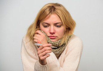 Woman feels badly ill sneezing. Girl in scarf hold thermometer and tissue close up. Measure...