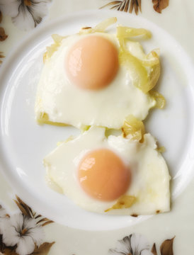 Top view on two fried with onions eggs on a plate