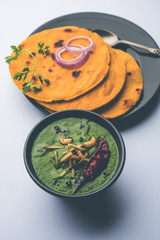 Makki di roti with sarson ka saag, popular punjabi main course recipe in winters made using corn breads mustard leaves curry. served over moody background. selective focus