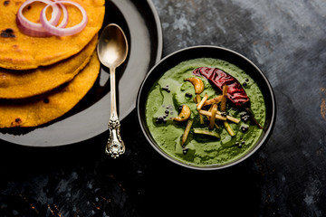 Makki di roti with sarson ka saag, popular punjabi main course recipe in winters made using corn breads mustard leaves curry. served over moody background. selective focus