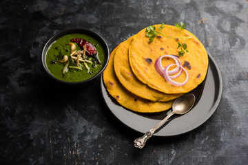 Makki di roti with sarson ka saag, popular punjabi main course recipe in winters made using corn breads mustard leaves curry. served over moody background. selective focus