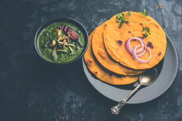 Makki di roti with sarson ka saag, popular punjabi main course recipe in winters made using corn breads mustard leaves curry. served over moody background. selective focus