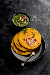 Makki di roti with sarson ka saag, popular punjabi main course recipe in winters made using corn breads mustard leaves curry. served over moody background. selective focus