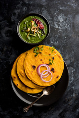 Makki di roti with sarson ka saag, popular punjabi main course recipe in winters made using corn breads mustard leaves curry. served over moody background. selective focus