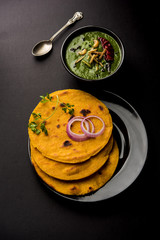 Makki di roti with sarson ka saag, popular punjabi main course recipe in winters made using corn breads mustard leaves curry. served over moody background. selective focus