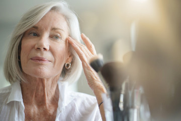 Attractive senior woman looking in the mirror