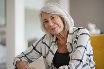 Fototapeta na wymiar Stylish senior woman sitting casually indoors and smiling