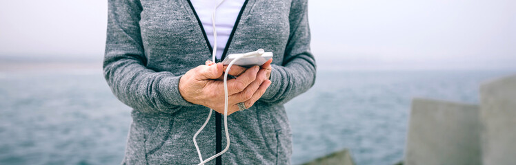 Midsection of senior sportswoman holding her smartphone