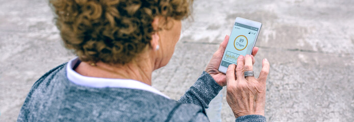 Back view of unrecognizable senior woman using smartphone by sea pier