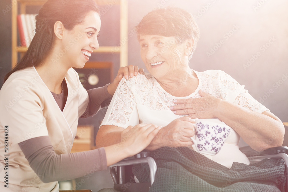 Wall mural Bright photo of smiling senior patient and her kind doctor at nursing home