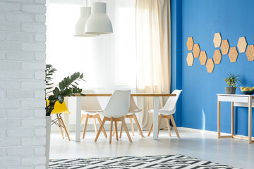 Bright blue and white dining room with table and chairs in voguish apartment