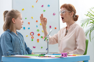 Speech therapist teaching vowels to a girl
