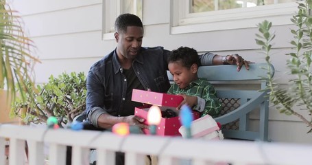 African American father giving son a christmas gift - Powered by Adobe