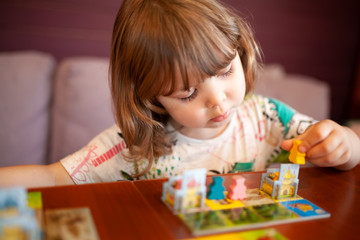 Adorable toddler girl playing board game indoors